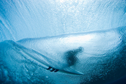 A behind the wave, underwater view of a surfer int he tube, in Micronesia.